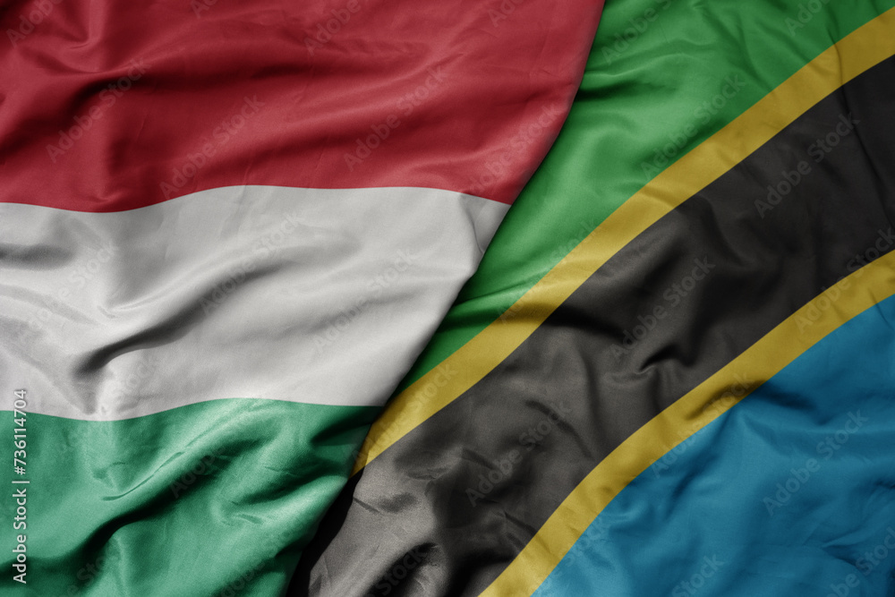 big waving national colorful flag of tanzania and national flag of hungary .