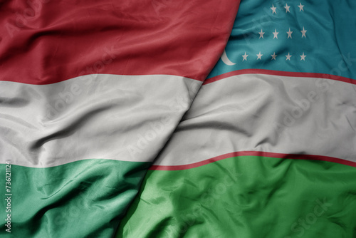 big waving national colorful flag of uzbekistan and national flag of hungary .