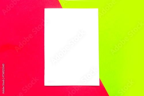 White paper blank on red and green geometric paper background. Copy space for the text