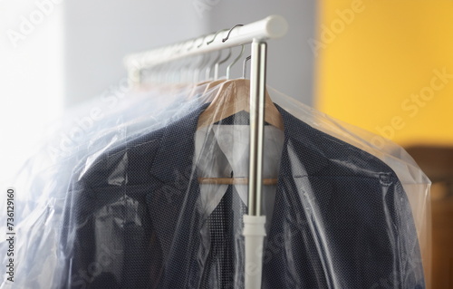 Obraz na płótnie Clothes in plastic bags hanging on hanger in laundry closeup. Dry cleaning service concept w salonie