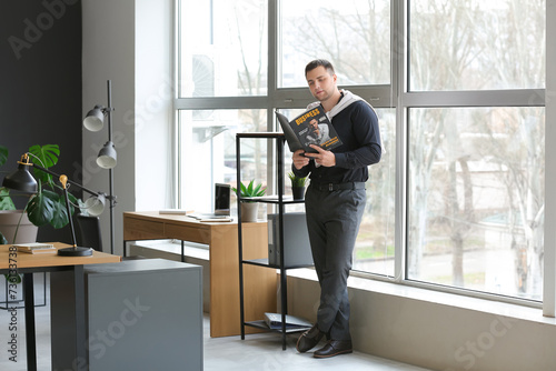 Young businessman reading magazine in office