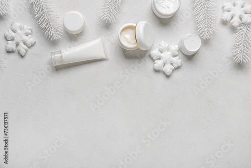 Cosmetic products with decorative snowflakes and fir branches on white background
