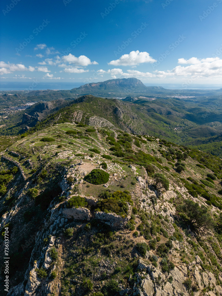 Fototapeta premium Aerial view of Castell d'Aixa and Castell de la Solana mountain ridge in a sunny blue sky, Lliber, Costa Blanca, Alicante, Spain - stock Photo