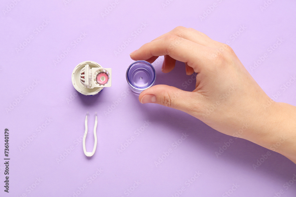 Female hand with cleaning case for contact lenses and tweezers on lilac background Female hand with cleaning case for contact lenses and tweezers on lilac background
