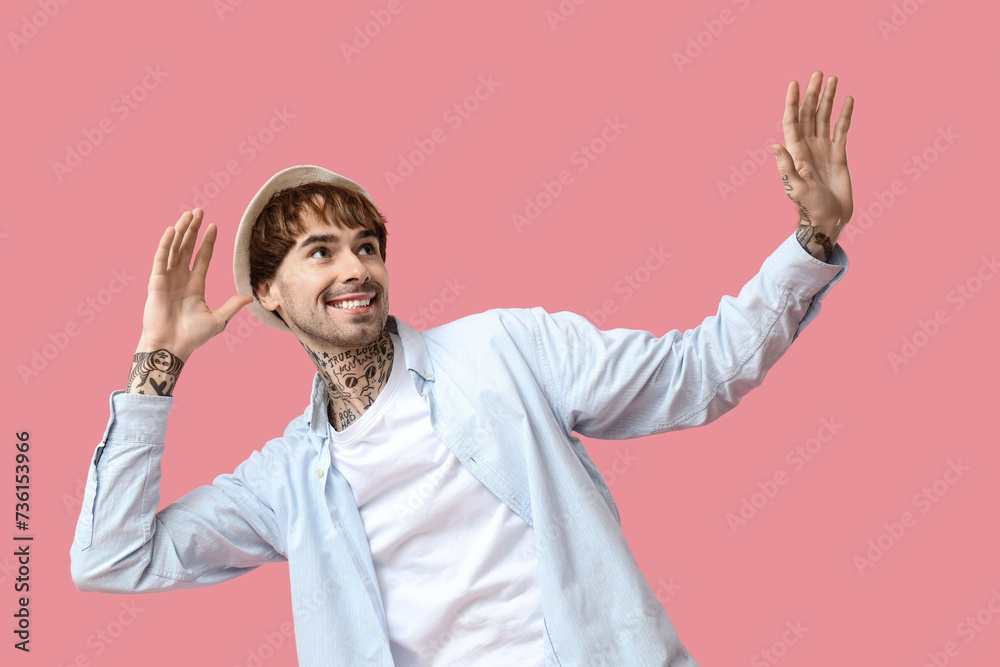 Young tattooed man dancing against pink background Young tattooed man dancing against pink background