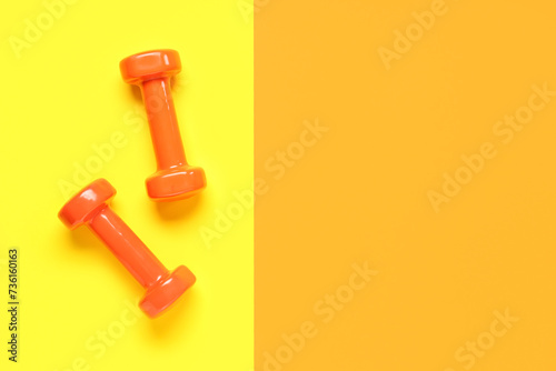 Pair of orange dumbbells on color background © Pixel-Shot