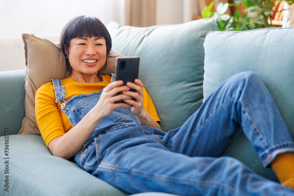 Woman using smart phone while relaxing at home Woman using smart phone while relaxing at home