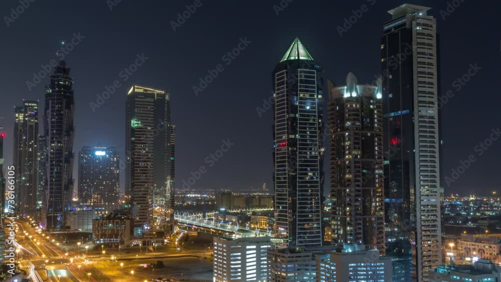 Business bay district skyline with modern architecture timelapse during all night from above. Aerial view of Dubai skyscrapers with blinking windows and illuminated towers near main highway traffic Business bay district skyline with modern architecture timelapse during all night from above. Aerial view of Dubai skyscrapers with blinking windows and illuminated towers near main highway traffic