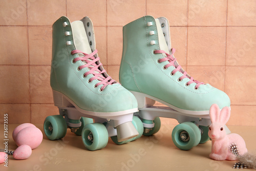 Vintage roller skates with Easter eggs, feathers and toy bunny on beige table