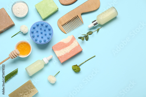 Hair scalp massagers with shampoo bars, different skincare products and flowers on blue background
