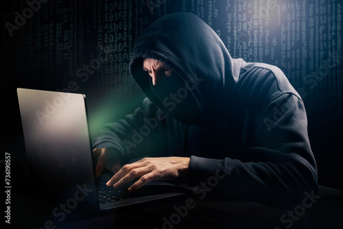Pirate informatique masqué en train de pirater un ordinateur portable et qui demande une rançon devant un écran vert photo