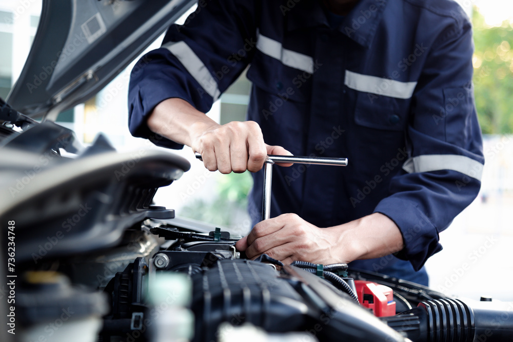 Mechanic are using the wrench to repair and maintenance auto engine at car repair shop,Car auto services and maintenance check concept.