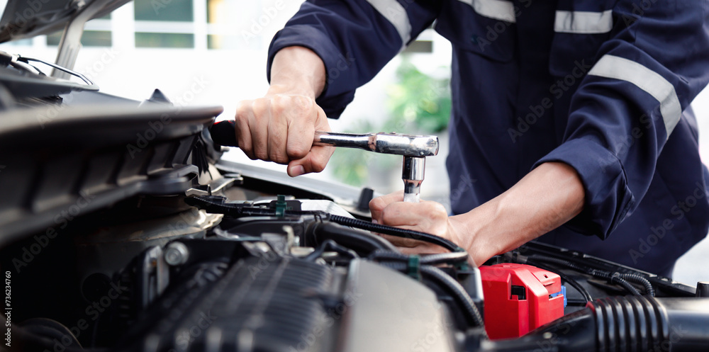 Mechanic are using the wrench to repair and maintenance auto engine at car repair shop,Car auto services and maintenance check concept.