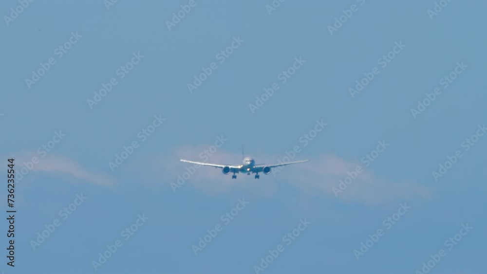 Long shot of an airliner approaching landing, front view. Jet airliner with unrecognizable livery descending, arriving. Wide-body aircraft in the blue sky Long shot of an airliner approaching landing, front view. Jet airliner with unrecognizable livery descending, arriving. Wide-body aircraft in the blue sky