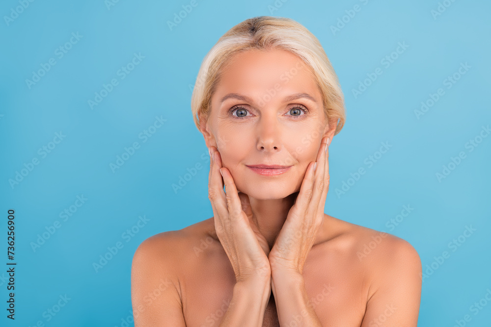 Photo of shiny pretty elderly lady naked shoulders arms touch cheekbones apply mask isolated blue color background