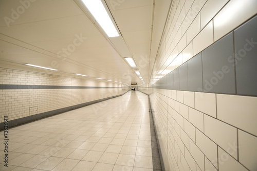 A very long white tiled underground passageway.