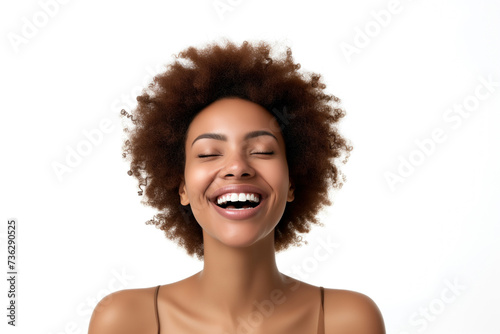 An exuberant woman with curly hair laughing joyfully.