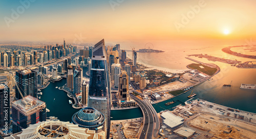 View of the Dubai skyline at sunset from above, warm earth colors in beautiful contrast to the dark teal of the water