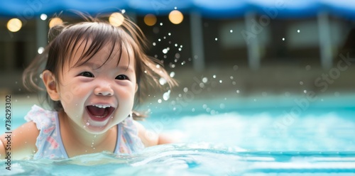 Happy Asian baby girl laughing and playing in the resort pool with her family © Danko