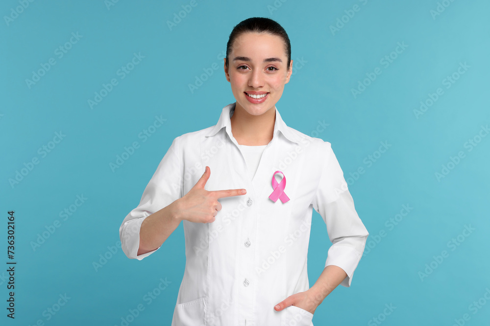 Mammologist pointing at pink ribbon on light blue background. Breast cancer awareness Mammologist pointing at pink ribbon on light blue background. Breast cancer awareness