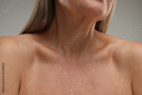 Mature woman with healthy skin on grey background, closeup