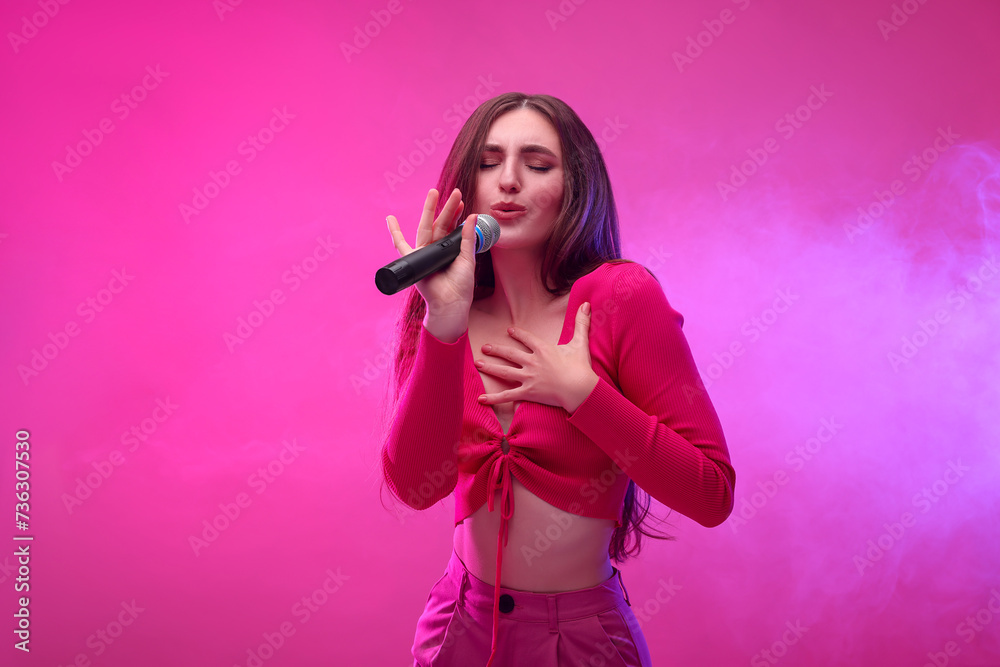 Beautiful woman with microphone singing on pink background Beautiful woman with microphone singing on pink background