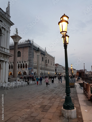 Lamppost with lights on in Venice on a late afternoon with the Doge’s Palace on the background