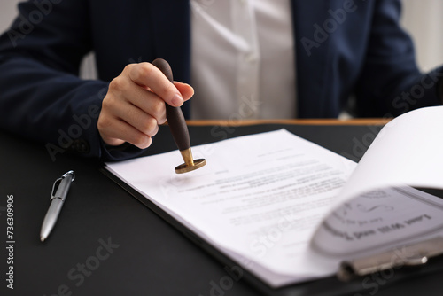 Notary sealing document at table in office, closeup