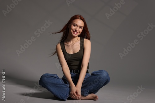 Beautiful young woman sitting on gray background © New Africa