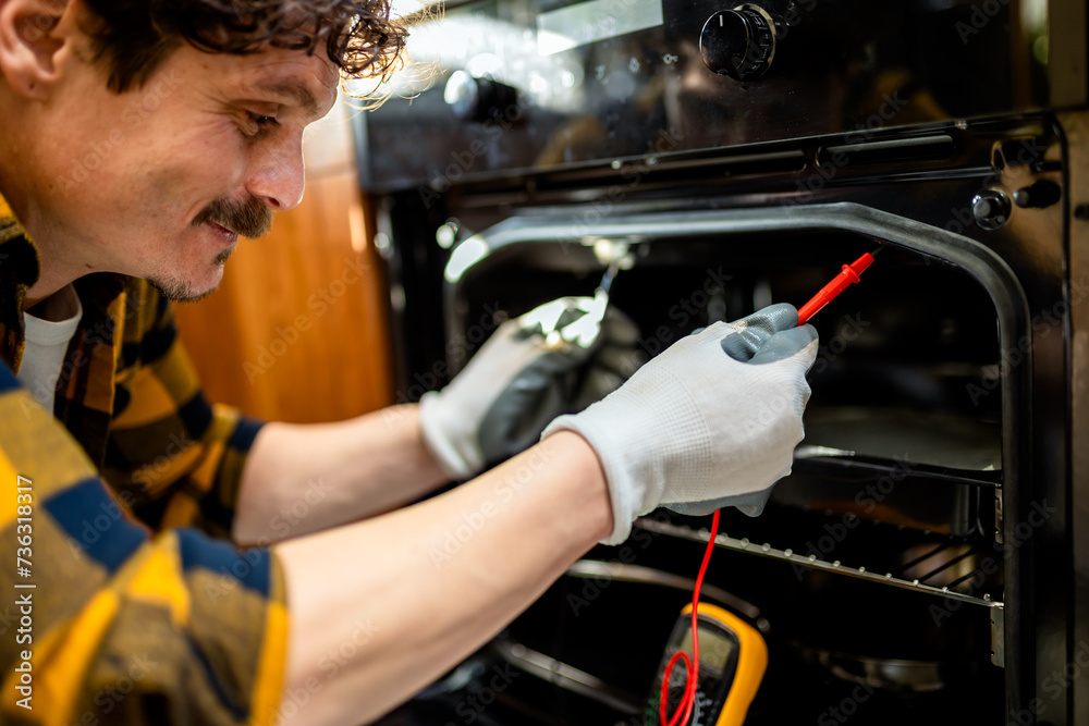 Latino man using multimeter for fixing stove. Latino man using multimeter for fixing stove.