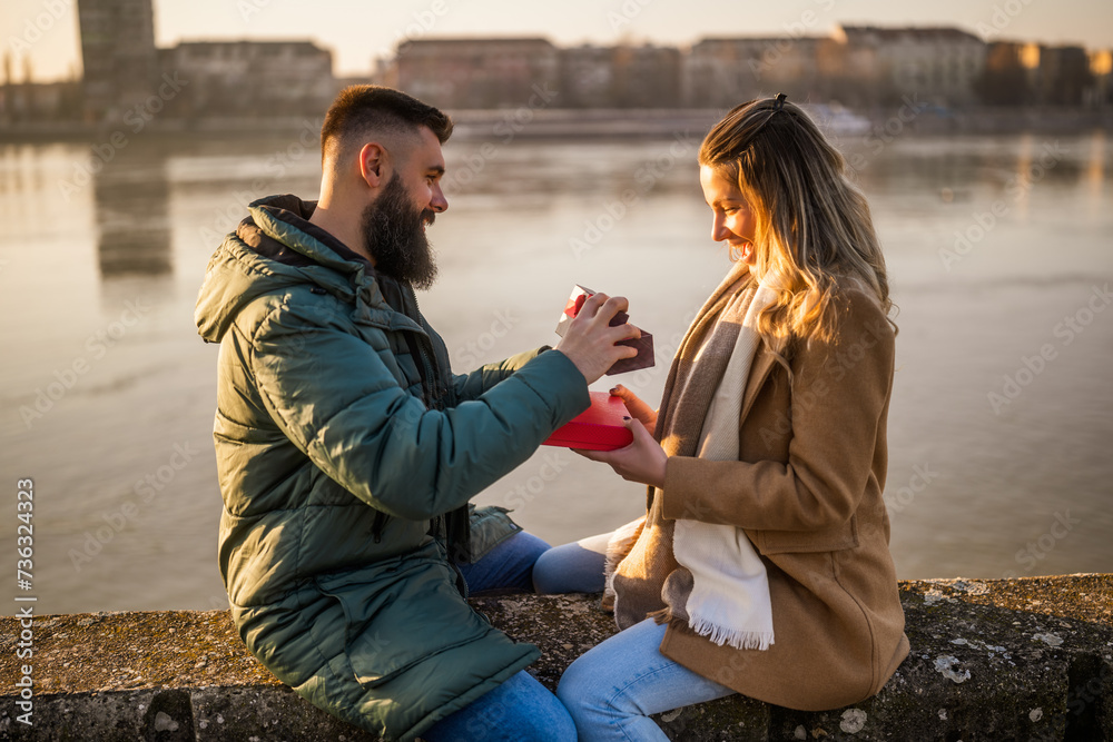 Man giving presents to his woman while they enjoy spending time together outdoor. Man giving presents to his woman while they enjoy spending time together outdoor.