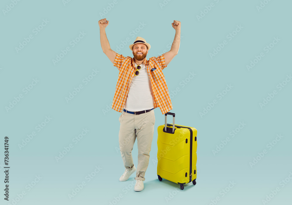 Happy man with a suitcase raises hands in excitement, exclaiming yes. Summer vacation and weekend getaways, traveler prepares for beach adventures and leisurely travels.