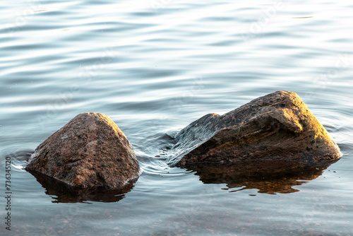 Zwei Steine, welche aus relativ ruhigem Wasser herausragen photo