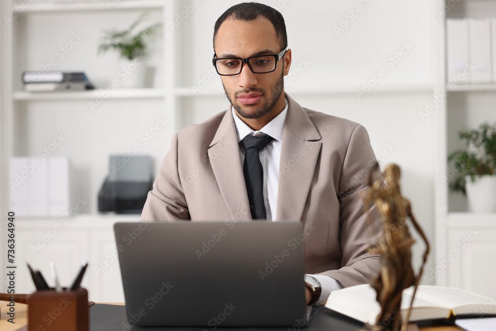 Serious lawyer working with laptop at table in office Serious lawyer working with laptop at table in office