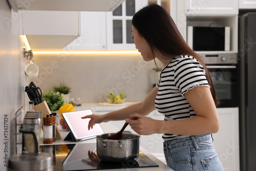 Woman looking at recipe on tablet while cooking in kitchen