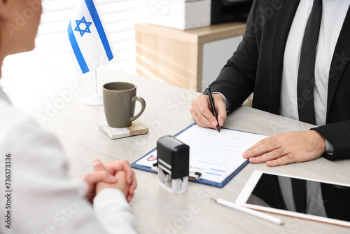 Immigration to Israel. Embassy worker signing application form at wooden table, closeup photo