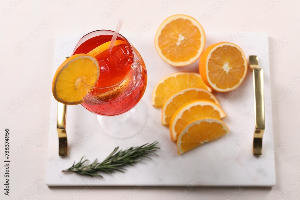 Glass of tasty Aperol spritz cocktail with orange slices and rosemary on white table, above view Glass of tasty Aperol spritz cocktail with orange slices and rosemary on white table, above view