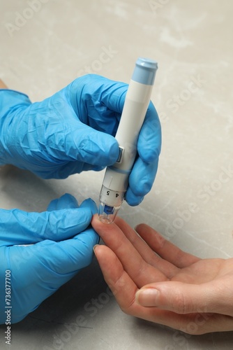Diabetes. glucose testing. Doctor using lancet pen at light table, closeup