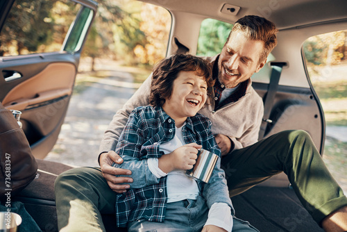 Father and son laughing together in car during a break on road trip photo