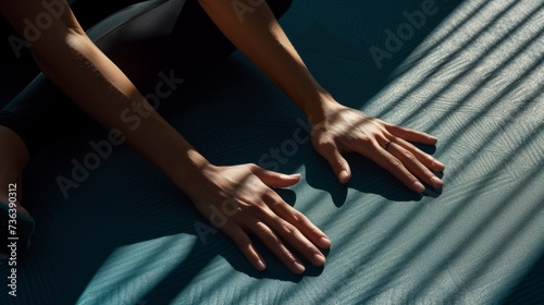 Two hands in a yoga position on a textured mat, casting long shadows, symbolizing a connection to self and discipline in practice