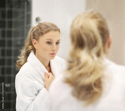 woman looking in the mirror in the bathroom and taking care of her skin.