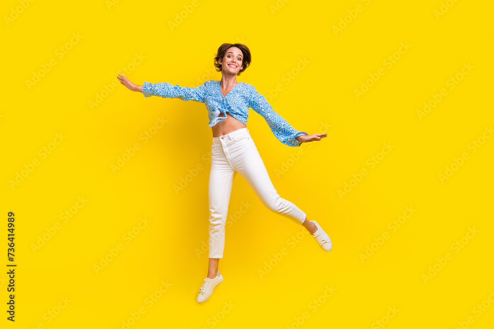 Full size photo of elegant dreamy girlish woman wear print blouse flying hold hands like wings isolated on yellow color background