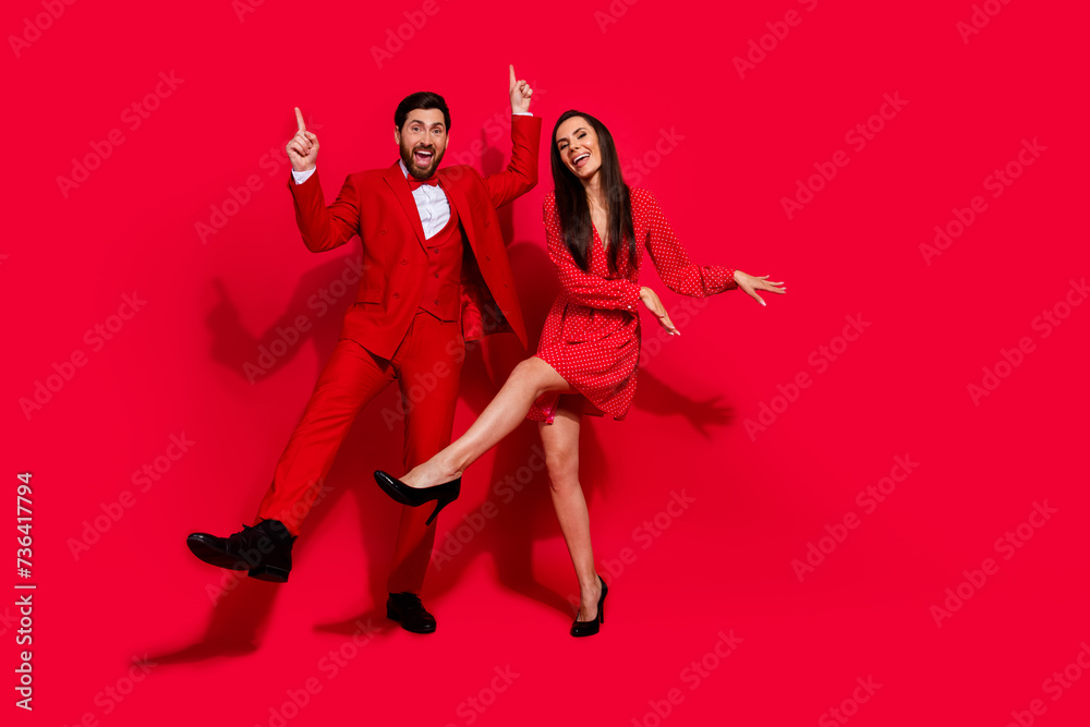 Full length photo of carefree cool classy people enjoy dancing empty space isolated on red color background