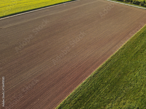 View from above of farm fields with soil and grass in the countryside 