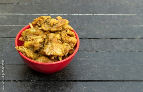 Mangsho Kosha or Indian Domestic Chicken Curry in a Red Bowl Isolated on Black Wooden Background with Copy Space photo