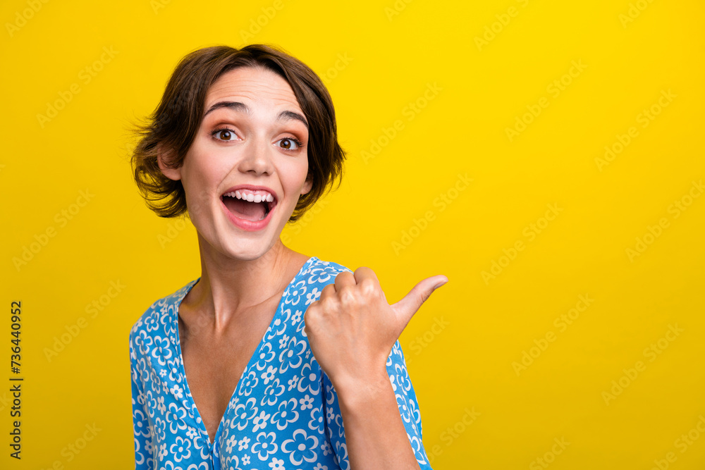 Portrait of ecstatic girl with short hairstyle wear blue stylish blouse directing at sale empty space isolated on yellow color background Portrait of ecstatic girl with short hairstyle wear blue stylish blouse directing at sale empty space isolated on yellow color background