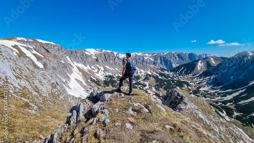Hiker man with panoramic view of majestic mountain peak Ringkamp in wild Hochschwab massif, Styria, Austria. Scenic hiking trail in remote Austrian Alps on sunny day. Wanderlust in alpine spring photo