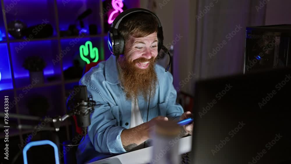 Irish redhead gamer guy streaming a nighttime mobile game session, smiling in a dark gaming room with tech-filled table Irish redhead gamer guy streaming a nighttime mobile game session, smiling in a dark gaming room with tech-filled table