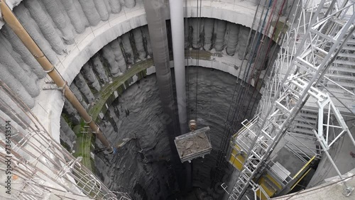 excavation from deep shaft well with crane, bucket and basket	