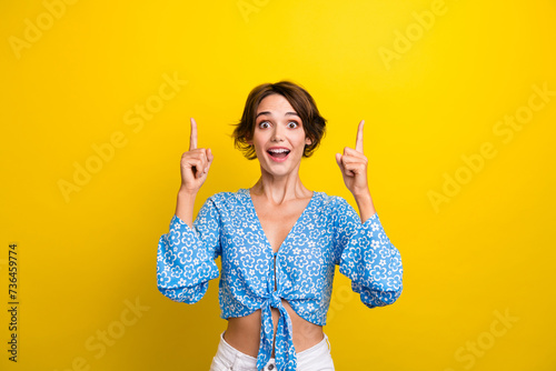 Photo of impressed funky woman wear flower print blouse showing two fingers empty space isolated yellow color background